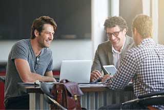 Tres compañeros de trabajo charlando y sonriendo