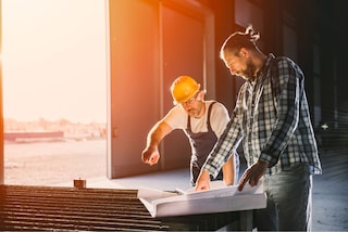 Hombres trabajando en construcción mirando planes